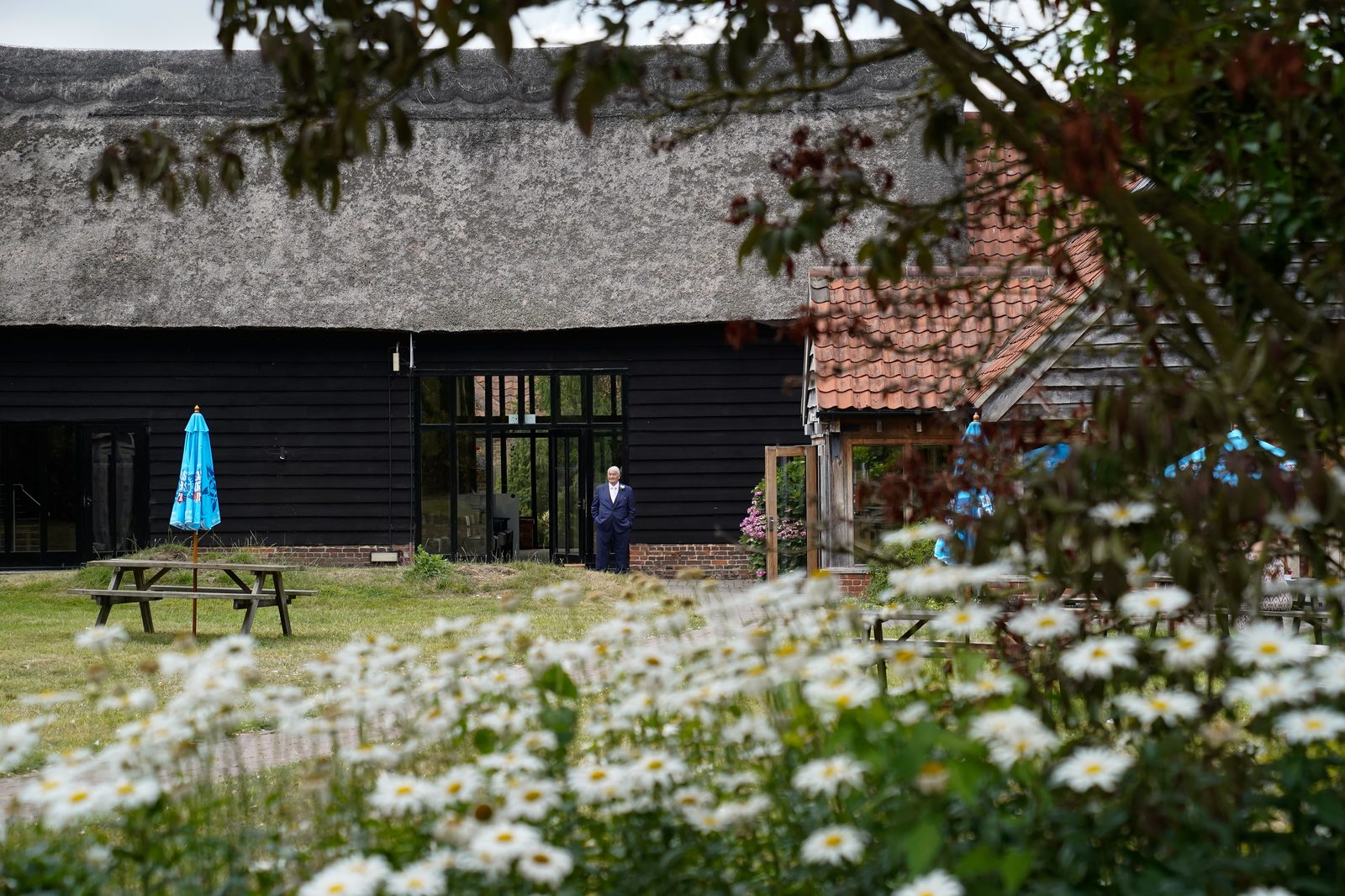 The thatched exterior of the Crooked Barn with wildflowers