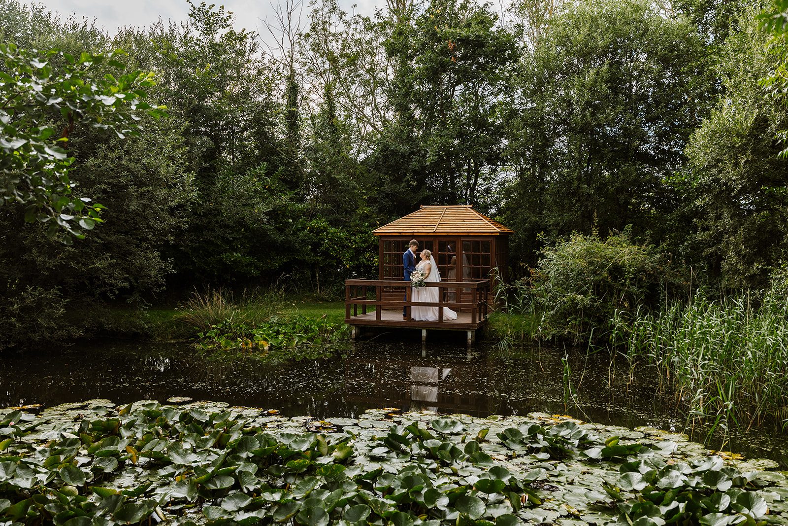 A thatched pavilion reflected in the lily pond