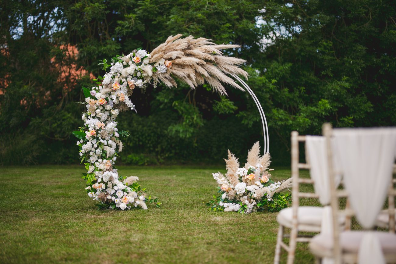 A pampas moon arch set for an outdoor ceremony