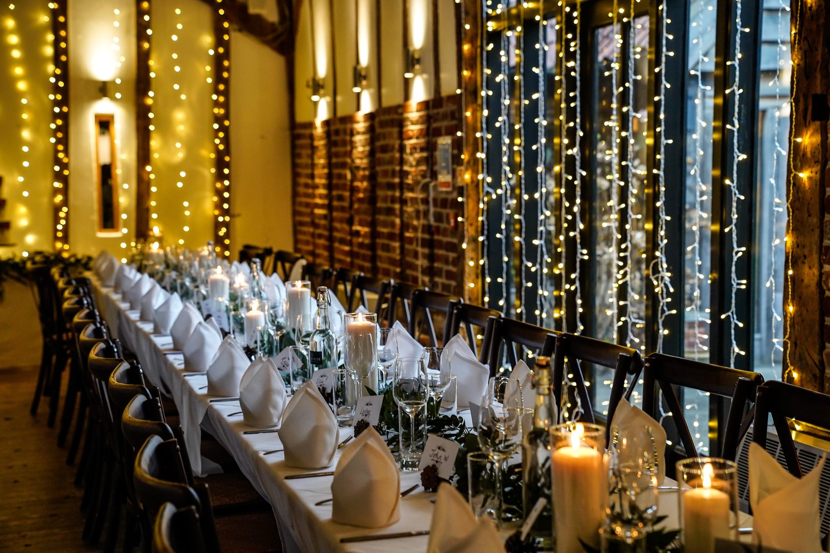 Long tables beneath a curtain of fairy lights inside the oak beamed Crooked Barn
